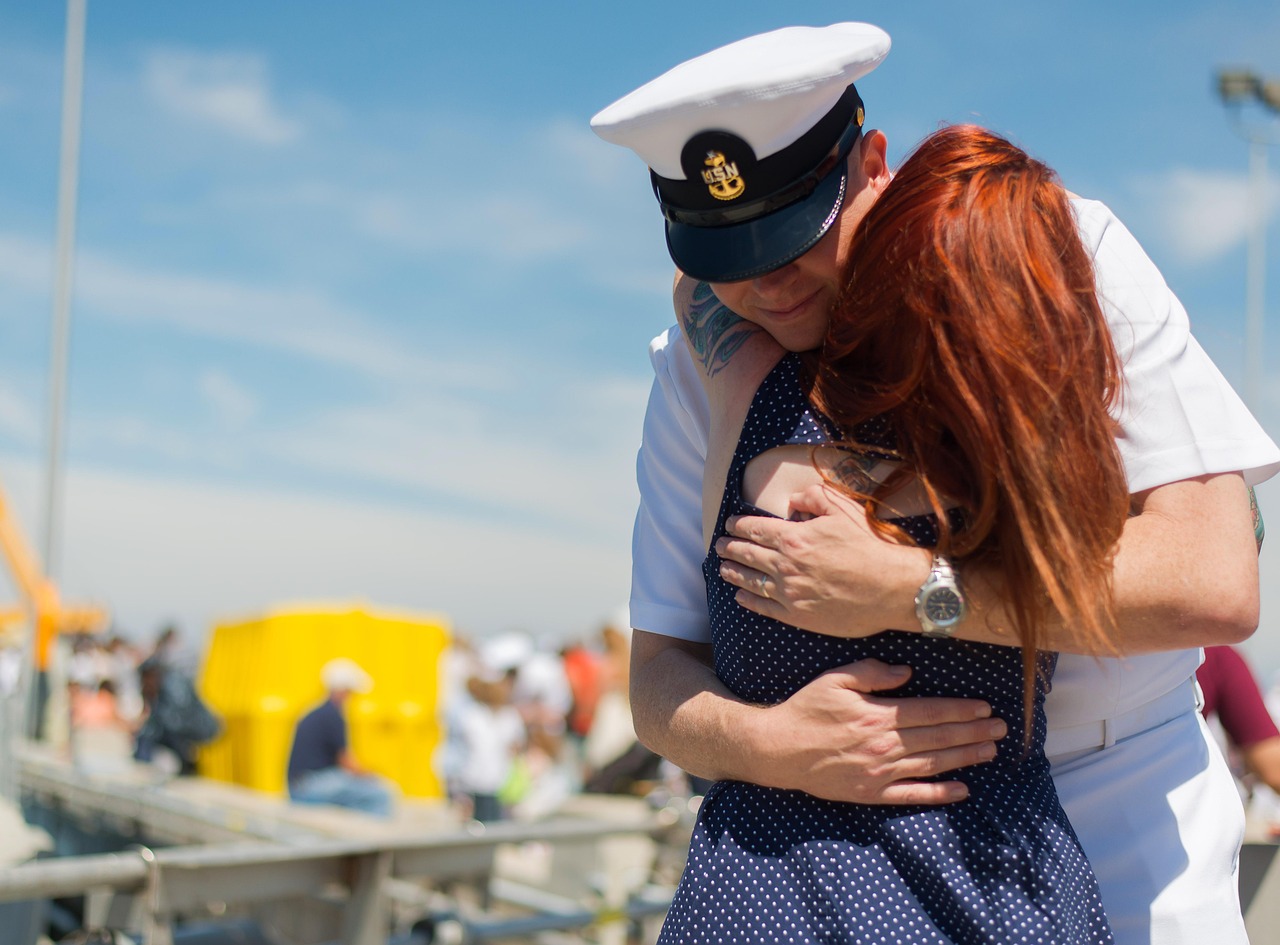 A returning sailor hugs his wife tightly at homecoming