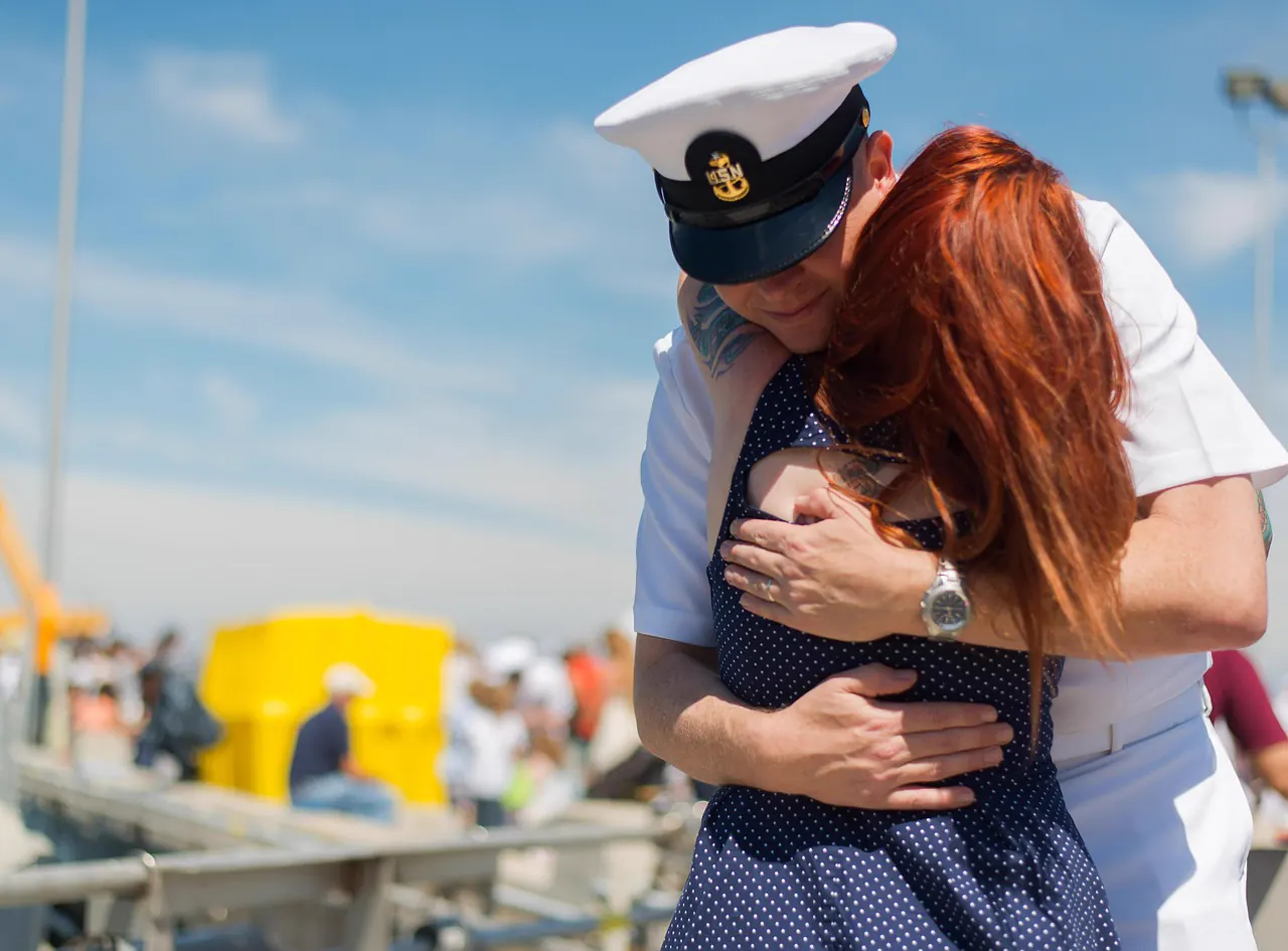 A returning sailor hugs his wife tightly at homecoming
