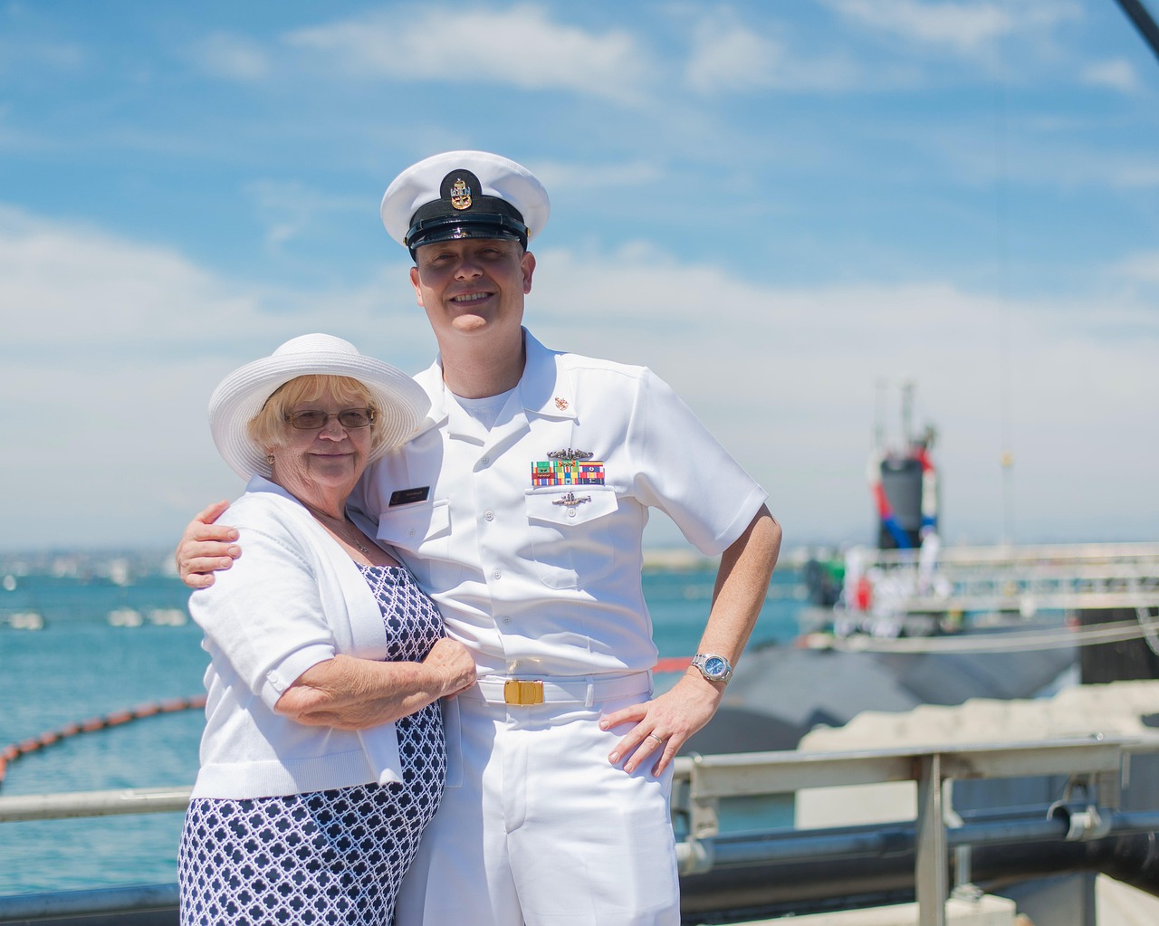 A Navy service member stands proudly with his mother at the pier